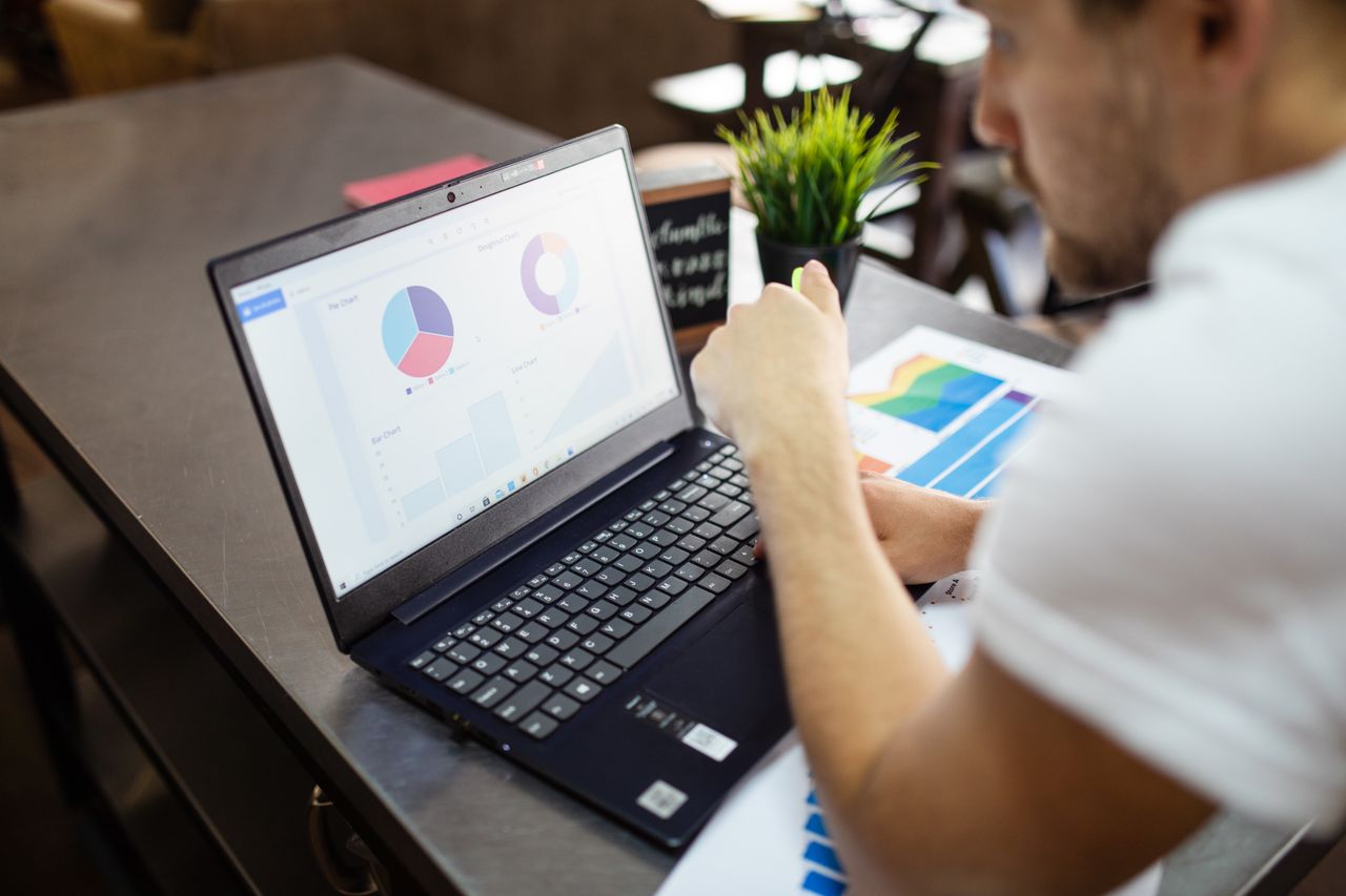 Un homme examine des graphiques et des courbes sur un ordinateur portable pour une analyse commerciale.
